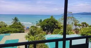 Vue du Kalaluna Bistro Hotel à Bahía Drake : petits pavillons en bois avec toit de palme, entourés de végétation tropicale et vue mer.
